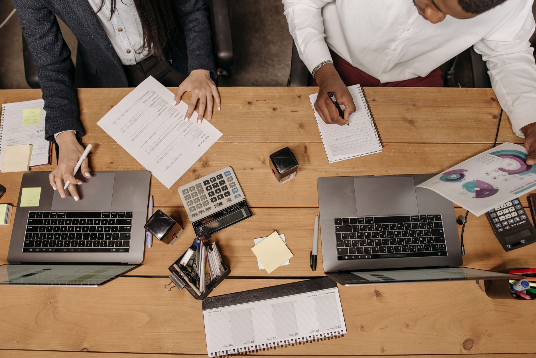 High-angle view of professionals working collaboratively with laptops and documents in an office. — Car Rental Insurance: Wha